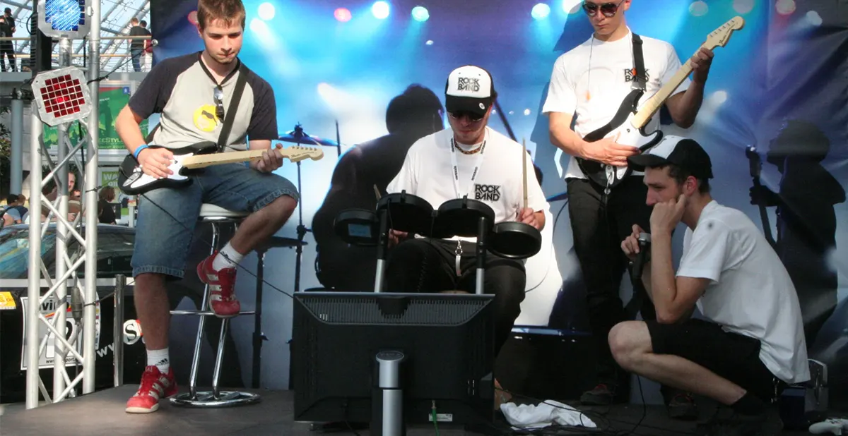 Three people on stage playing Rock Band